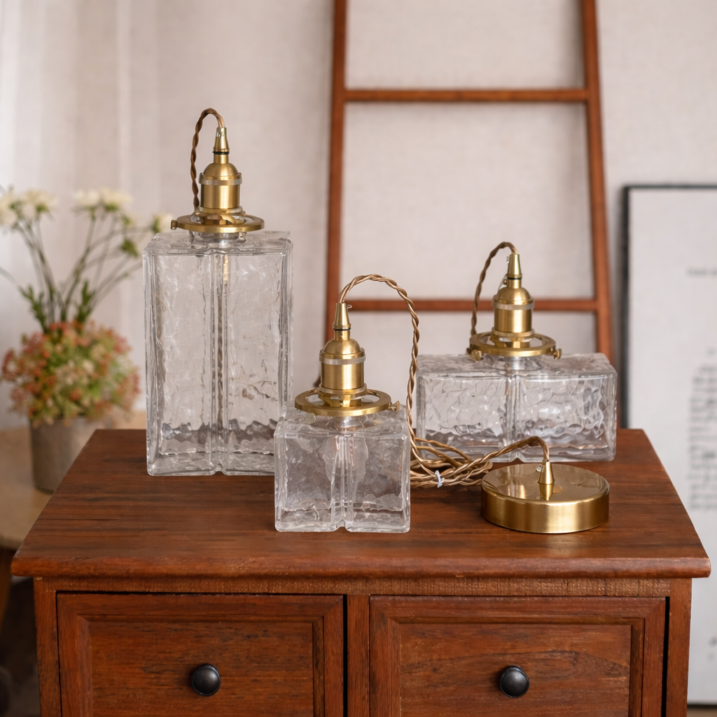 Set of three vintage-style glass lamps with gold accents on a wooden surface.