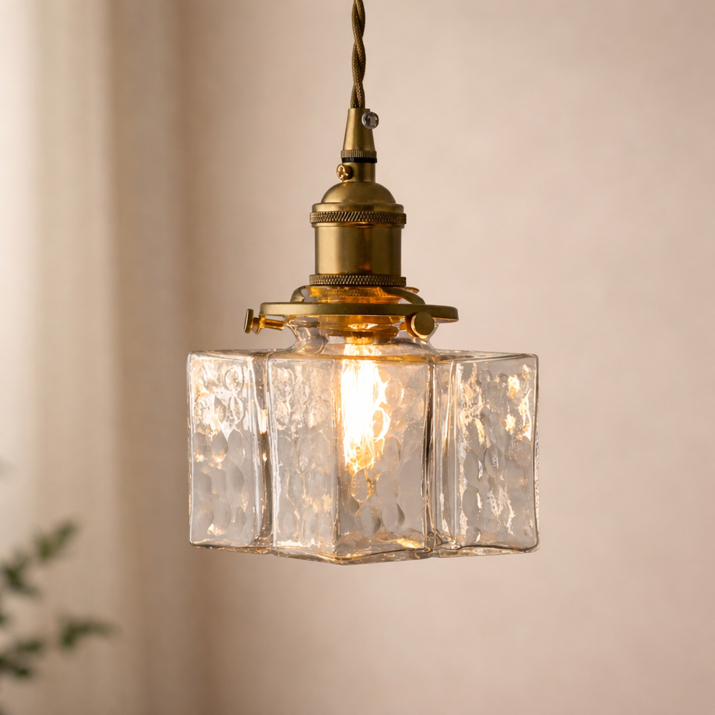 Vintage-style pendant light with clear glass shade and brass fixture on a neutral background