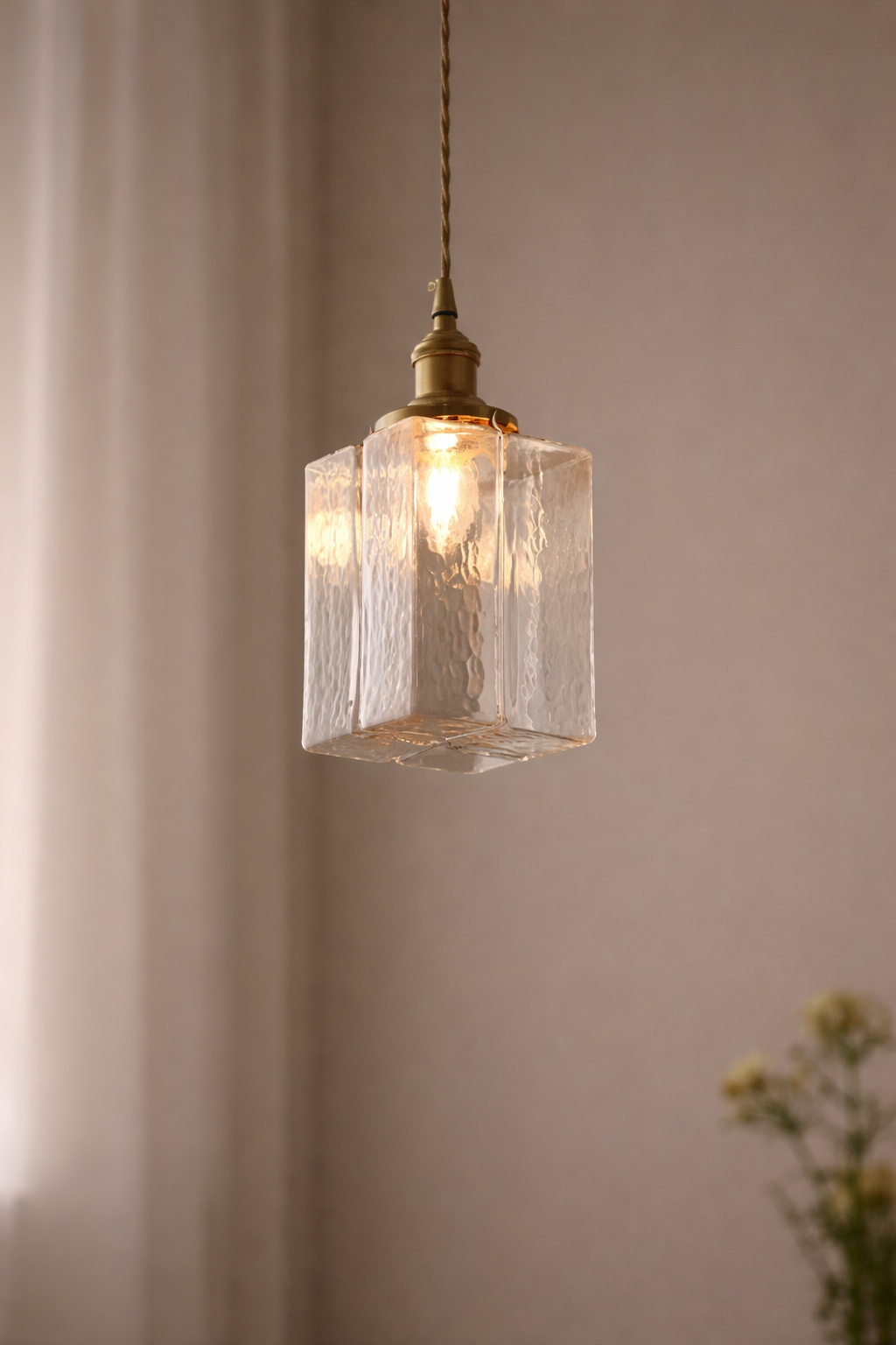 Pendant light with textured glass shade and brass fixture against a neutral background