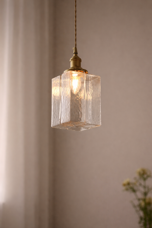 Pendant light with textured glass shade and brass fixture against a neutral background